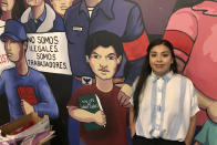 In this Dec. 6, 2019 photo, Reyna Lopez, the executive director of a farm worker union known as PCUN — an acronym in Spanish for Pine Workers and Farmers United of the Northwest — poses for a photo in front of a mural at the union's headquarters in Woodburn, Ore. Lopez said that a recent van crash that killed three Christmas tree farm workers from Guatemala shed light on "invisible work" happening in Oregon, which has the U.S.'s largest Christmas tree industry. (AP Photo/Andrew Selsky)