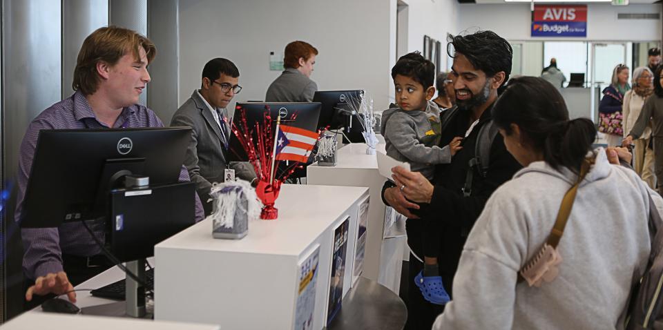 Parti Gandhi, right, of Newark, holds his son, Laksh, 2, and waits with his wife, Aisha, far right, to check-in for their Avelo Airlines flight to Puerto Rico on Nov. 15, 2023.