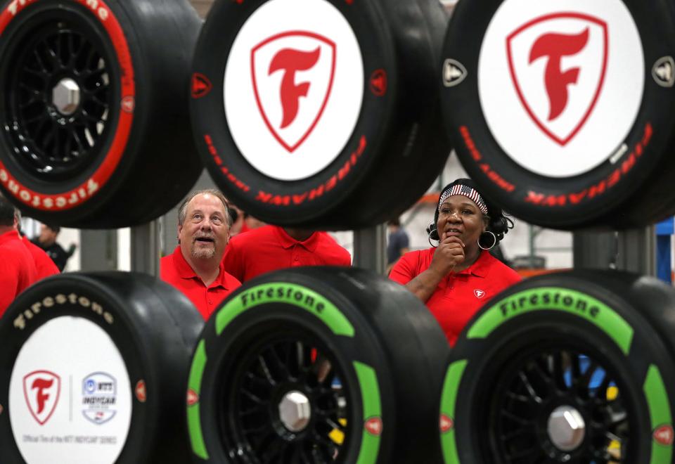 Firestone tire curing department workers Chris Krause, left, and Bonita Barnett, right, take a look at the Firestone Firehawk race tires on display during the grand opening ceremony for the Bridgestone Advanced Tire Production Center in Akron on Wednesday.