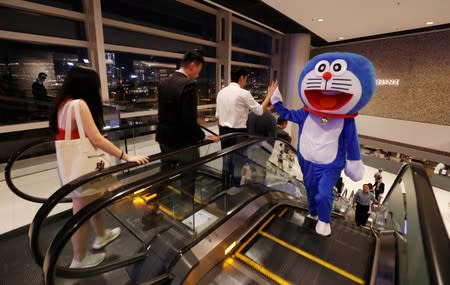 A man wearing a Doraemon mascot costume gives high five to a man during a protest at International Finance Center (IFC) in Hong Kong