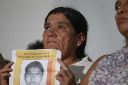 A relative of the 43 missing students of Ayotzinapa Teacher Training College Raul Isidro Burgos holds a poster in a news conference in Mexico City October 29, 2014. REUTERS/Edgard Garrido