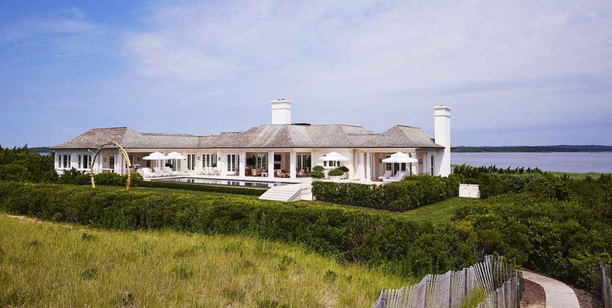 white house on the ocean with green surrounding it