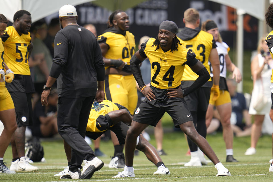 Pittsburgh Steelers cornerback Joey Porter Jr. (24) stretches as coach Mike Tomlin, left, walks past during the NFL football team's training camp in Latrobe, Pa., Thursday, July 27, 2023. (AP Photo/Gene J. Puskar)