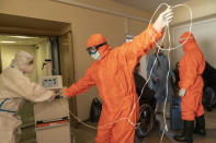 Medical workers wearing special suits to protect against coronavirus setup a medical equipment for a patient in a hospital in Kolomyia, western Ukraine, Tuesday, Feb. 23, 2021. After several delays, Ukraine finally received 500,000 doses of the AstraZeneca vaccine marketed under the name CoviShield, the first shipment of Covid-19 vaccine doses. The country of 40 million is one of the last in the region to begin inoculating its population. (AP Photo/Evgeniy Maloletka)