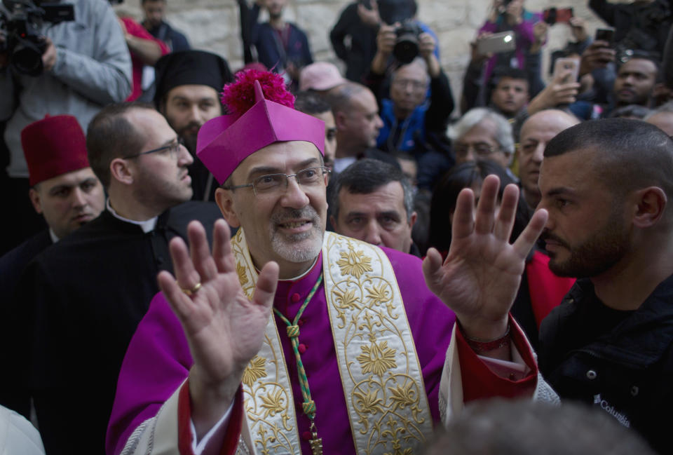 Christians celebrate the arrival of Archbishop Pierbattista Pizzaballa, the top Roman Catholic cleric in the Holy Land, center, after he crossed an Israeli military checkpoint from Jerusalem ahead of midnight Mass at the Church of the Nativity, traditionally recognized by Christians to be the birthplace of Jesus Christ, in the West Bank city of Bethlehem, Monday, Dec. 24, 2018. Palestinians are preparing to host pilgrims from around the world in celebrating Christmas in the West Bank city of Bethlehem. (AP Photo/Nasser Nasser)