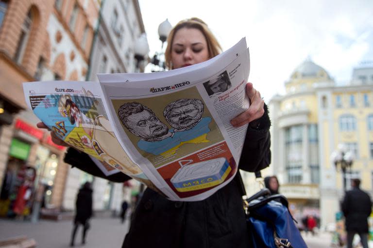 A woman looks through her copy of the first issue of satirical weekly magazine Sharzh i Pero as she walks along a street in central Moscow on April 21, 2015