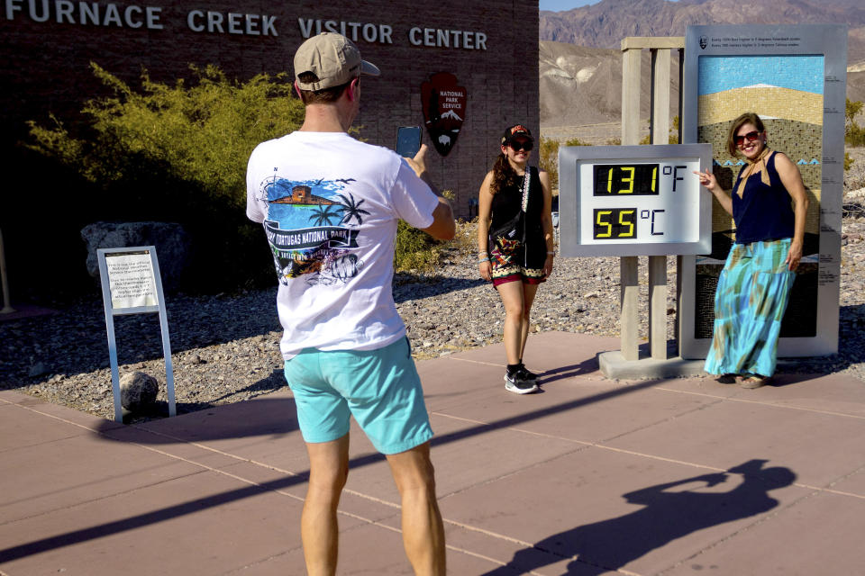 Matt Fiedler takes a photo of daughter Sally Fiedler, left, and wife Cecilia Fiedler by the thermometer at the Furnace Creek Visitor Center, Tuesday, July 9, 2024, in Death Valley, Calif. European tourists and adventurers from around the U.S. are still being drawn to Death Valley National Park, even though the desolate region known as one of the Earth's hottest places is being punished by a dangerous heat wave. (AP Photo/Ty ONeil)
