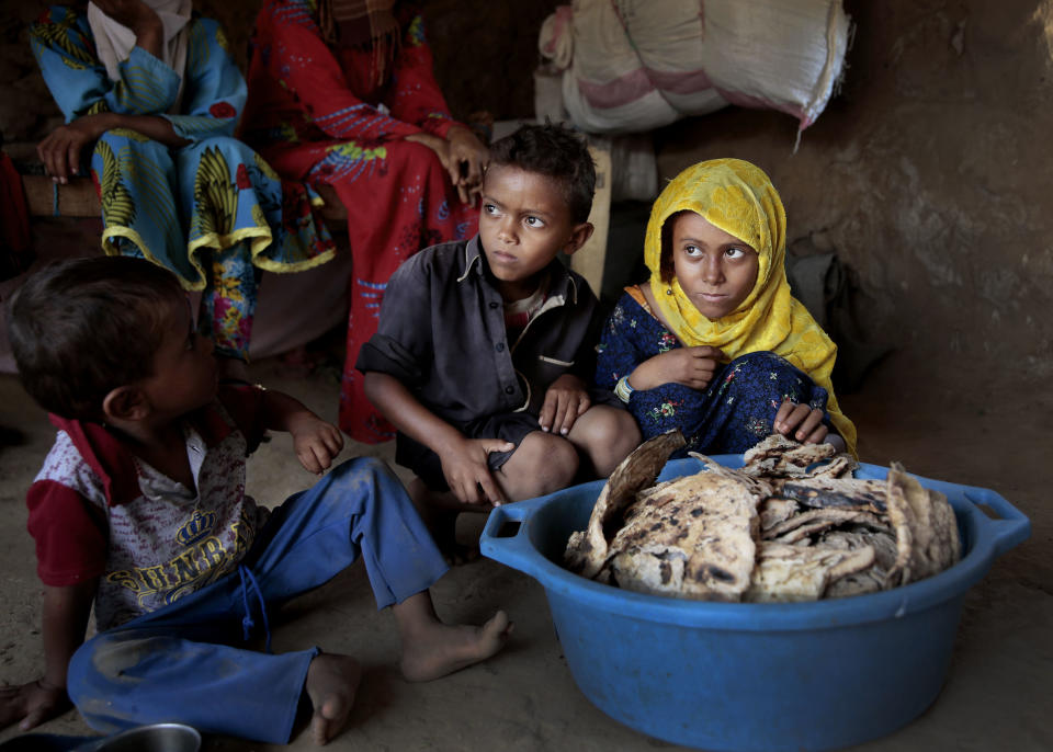 FILE - In this Oct. 1, 2018 file photo, children sit in front of moldy bread in their shelter, in Aslam, Hajjah, Yemen. The U.N. children’s agency says that millions of Yemeni children could be pushed to “the brink of starvation” as the coronavirus pandemic sweeps across the war-torn Arab country amid a huge drop in humanitarian aid funding. UNICEF on Friday, June 26, 2020 released a new report, “Yemen five years on: Children, conflict and COVID-19.” (AP Photo/Hani Mohammed, File)