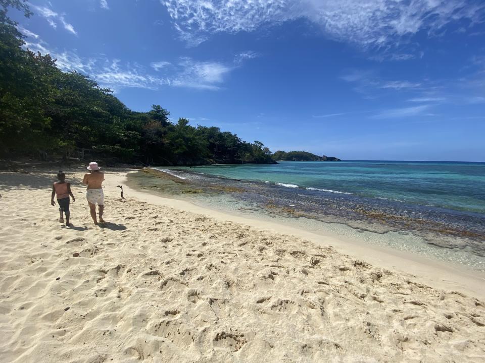 Two people walk along a deserted beach