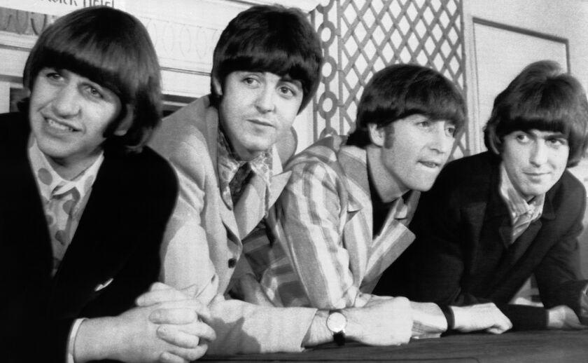 A black and white photo of four men leaning on a ledge in the 1960s