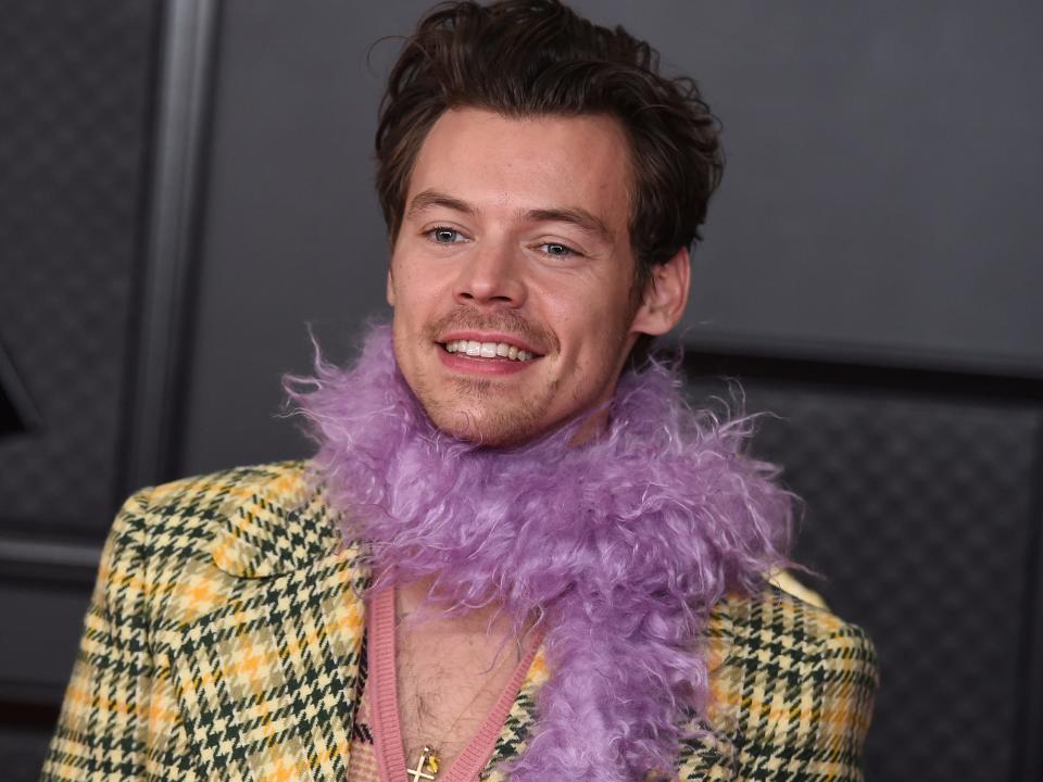 Harry Styles wearing a plaid yellow jacket and light-purple feather boa at the 2021 Grammys.