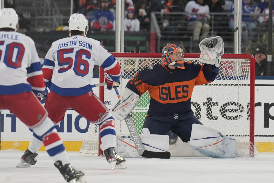 New York Islanders goaltender Ilya Sorokin, right, makes a save during the second period of an NHL Stadium Series hockey game against the New York Rangers in East Rutherford, N.J., Sunday, Feb. 18, 2024. (AP Photo/Seth Wenig)