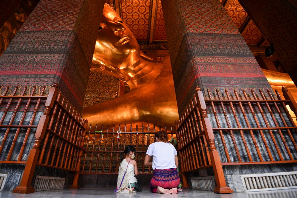 泰國宋干節（潑水節）期間，民眾戴口罩在佛像前祈禱。圖片來源：Reuters。