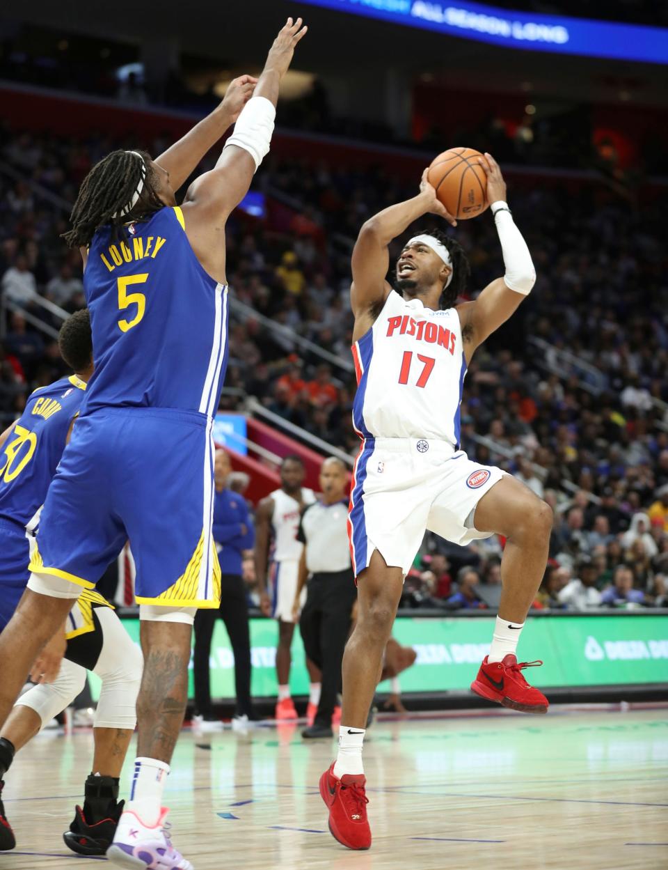 Detroit Pistons guard Stanley Umude (17) scores against Golden State Warriors forward Kevon Looney (5) during fourth-quarter action at Little Caesars Arena in Detroit on Monday, Nov. 6, 2023.