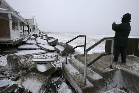 A bystander takes a photograph where the storm surge from a winder blizzard broke through a sea wall at high tide in Marshfield, Massachusetts January 27, 2015. REUTERS/Brian Snyder