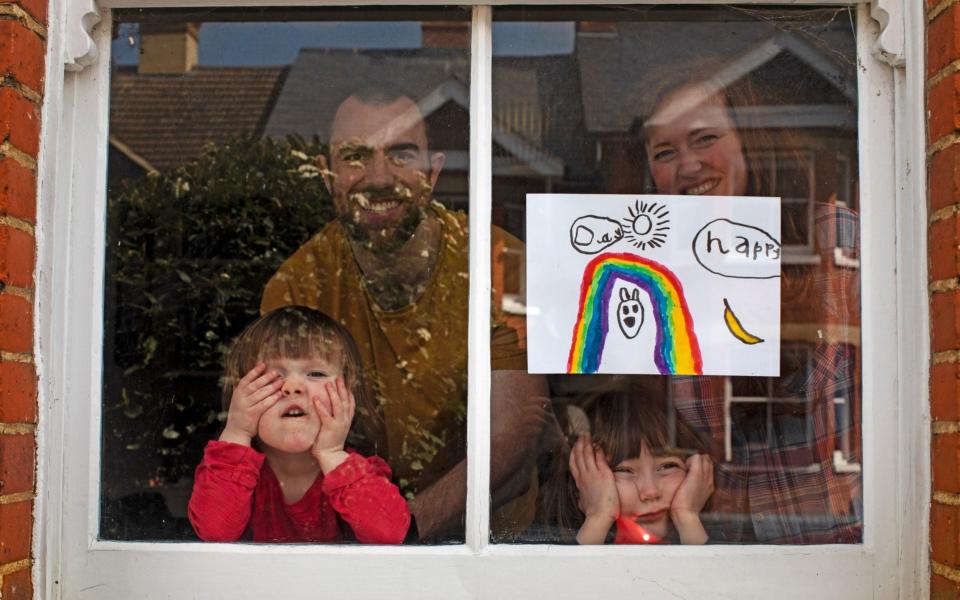 Amelie and her sister, Camille, look out from their front window in the COVID-19 coronavirus lockdown along with their parents, Victoria and Damian Kerr, in Berkhamsted, England -&nbsp;Lockdown saved no lives and may have cost them, Nobel Prize winner believes - AP