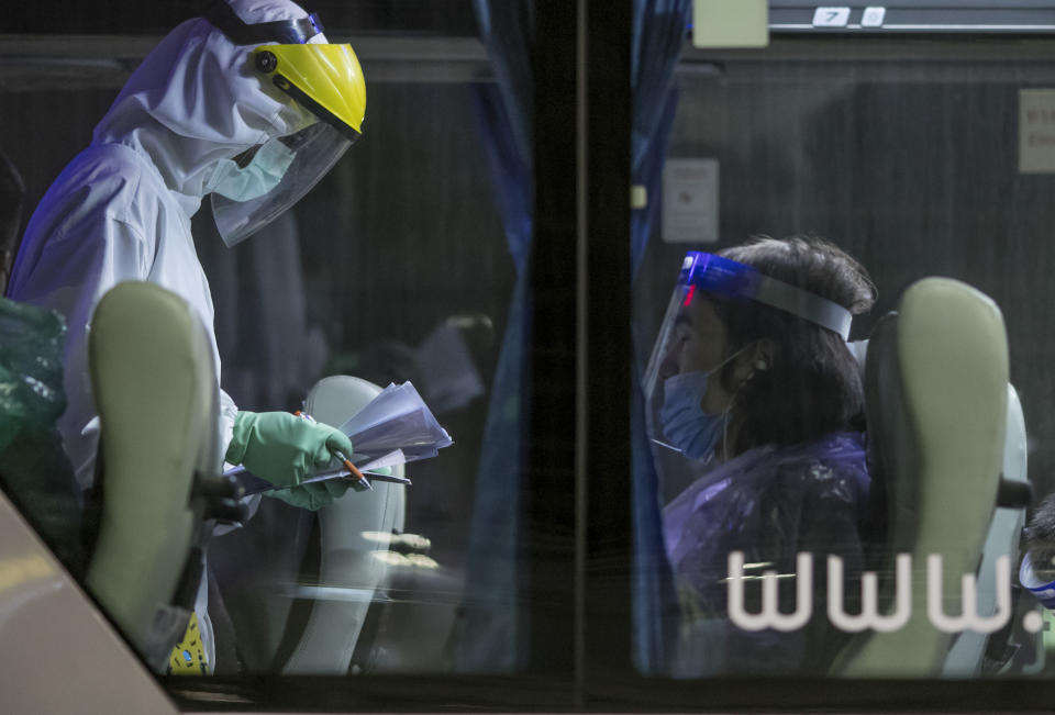 A public health worker gathers information from Chinese tourists from Shanghai, who arrived at Suvarnabhumi airport on special tourist visas, in Bangkok, Thailand, Tuesday, Oct. 20, 2020. Thailand on Tuesday took a modest step toward reviving its coronavirus-battered tourist industry by welcoming 39 visitors who flew in from Shanghai, the first such arrival since normal traveler arrivals were banned almost seven months ago. (AP Photo/Wason Wanichakorn)