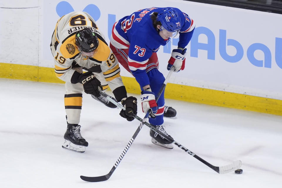 Boston Bruins center Johnny Beecher (19) and New York Rangers center Matt Rempe (73) pursue the puck in the first period of an NHL hockey game, Thursday, March 21, 2024, in Boston. (AP Photo/Steven Senne)