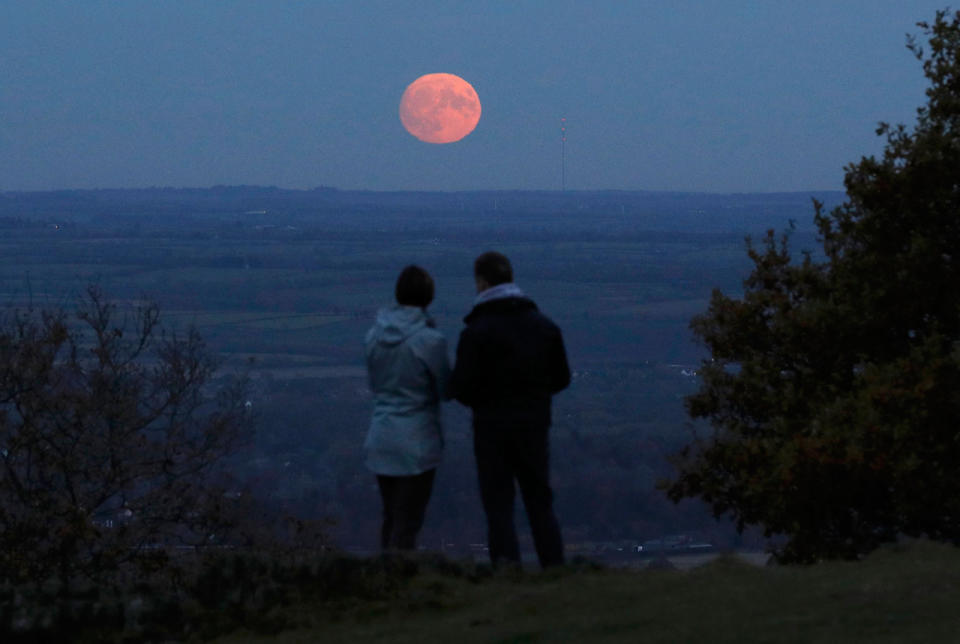 Una pareja mira la luna levantarse un día antes del espectáculo “supermoon” en Beacon Hill cerca de Loughborough, Gran Bretaña, el 13 de noviembre de 2016. (REUTERS / Darren Staples)