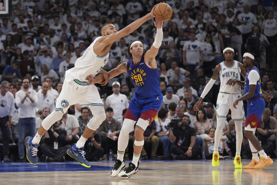 Minnesota Timberwolves center Rudy Gobert, left, and Denver Nuggets forward Aaron Gordon (50) reach for the ball during the second half of Game 6 of an NBA basketball second-round playoff series Thursday, May 16, 2024, in Minneapolis. (AP Photo/Abbie Parr)