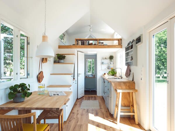 The interior ceiling height of 10 feet allows a bed to be lofted above the bathroom at one end of the unit. The stairs leading up to the sleeping area double as storage cabinets.