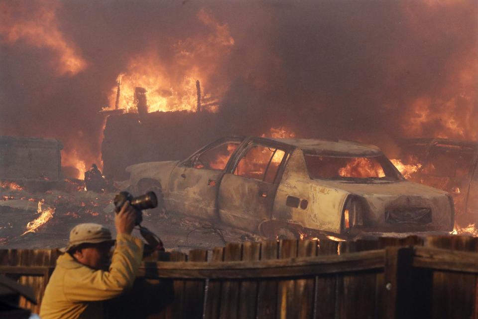 FILE - In this Dec. 5, 2017, file photo, a news photographer takes pictures of a wildfire in the Lake View Terrace area of Los Angeles. Photographers have captured searing, intimate images of active and dangerous wildfires burning California, due in large part to a state law that guarantees press virtually unfettered access to disaster sites in evacuated areas off-limits to the public. That's not the case everywhere as rules about media access vary by state, and even by government agency. (AP Photo/Chris Carlson, File)