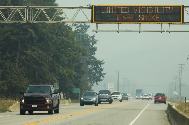 Vehicles pass an electronic sign on Highway 1 warning of limited visibility on roads due to dense wildfire smoke in Sicamous