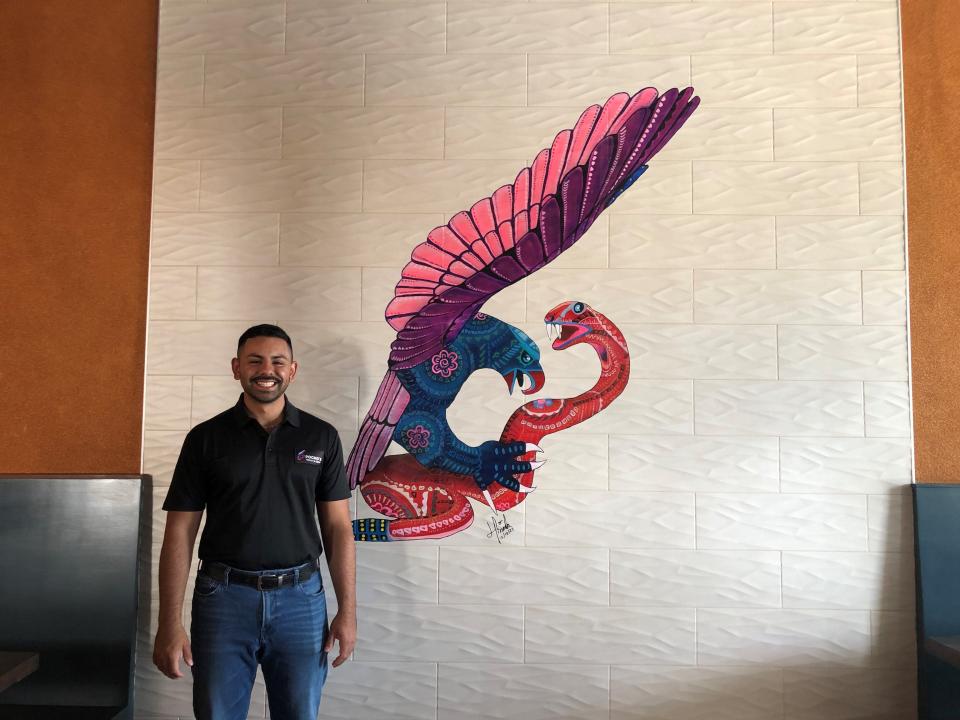 Ramon Reyes, owner and operator of Pocho's Tequila and Cocina, in front of the restaurant's logo that features a snake and eagle. Reyes selected the two animals for the logo because they are both featured on the Mexican flag.