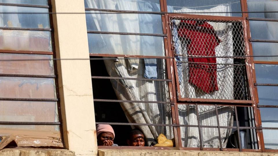 Residents watch from a window the scene of a deadly blaze, in Johannesburg