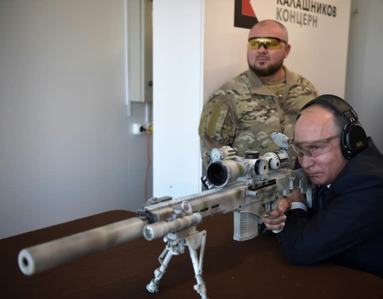 Russian President Vladimir Putin looks through the scope as he shoots a Chukavin sniper rifle (SVC-380) during a visit to a military park