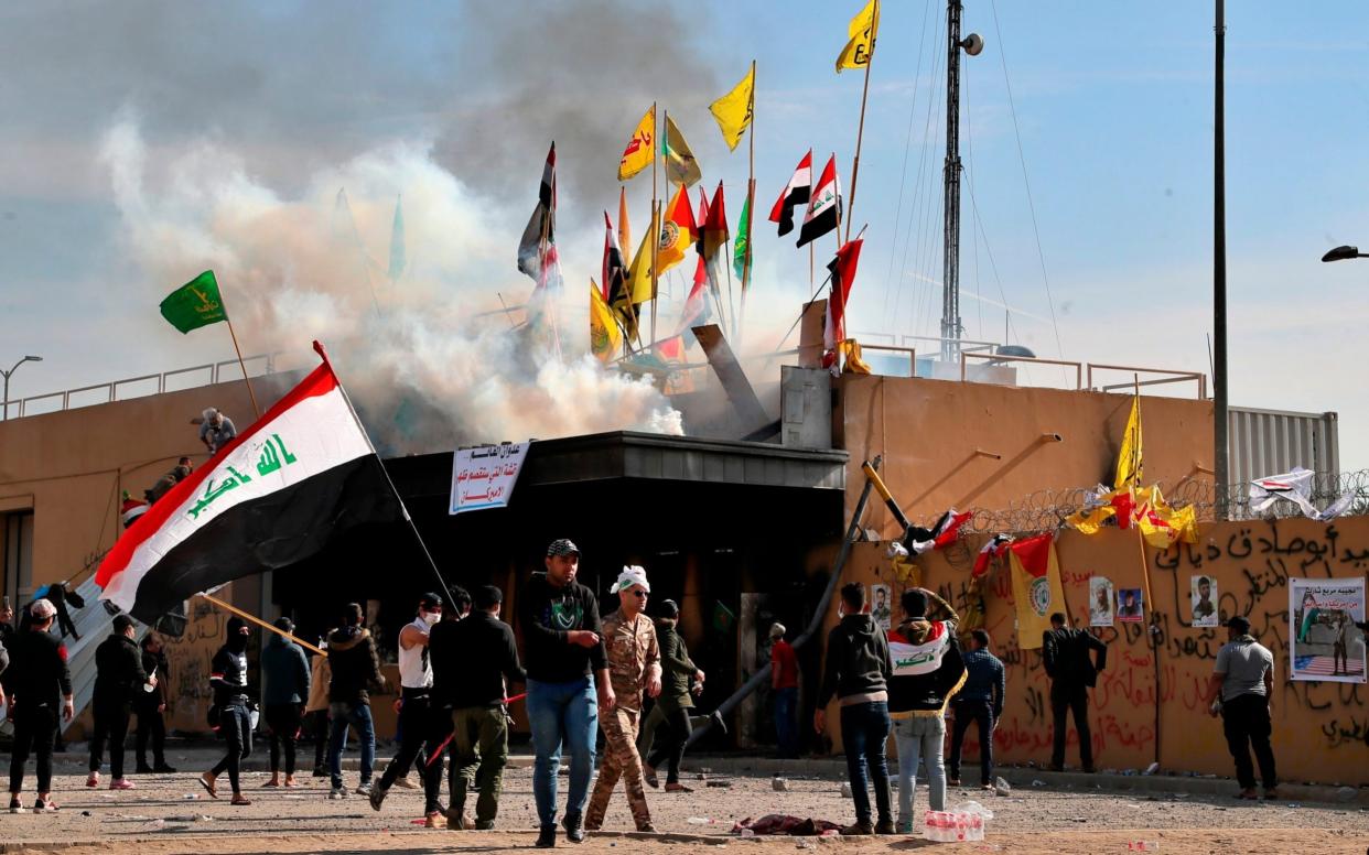 Pro-Iranian militiamen and their supporters set a fire while US soldiers fired tear gas during a sit-in in front of the US embassy in Baghdad - AP