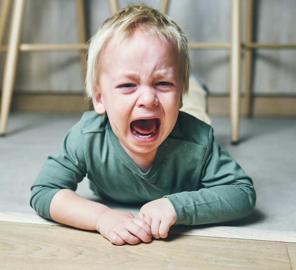 A young boy lies on the floor and cries