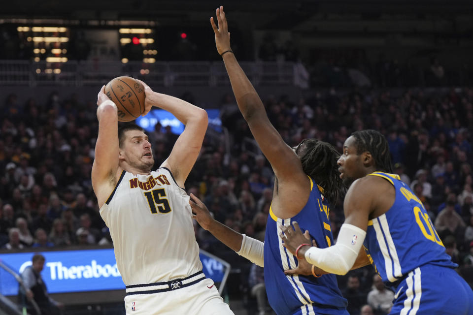 Denver Nuggets center Nikola Jokic (15) looks to pass as Golden State Warriors forward Kevon Looney, center, and forward Jonathan Kuminga, right, defend during the first half of an NBA basketball game Thursday, Jan. 4, 2024, in San Francisco. (AP Photo/Loren Elliott)