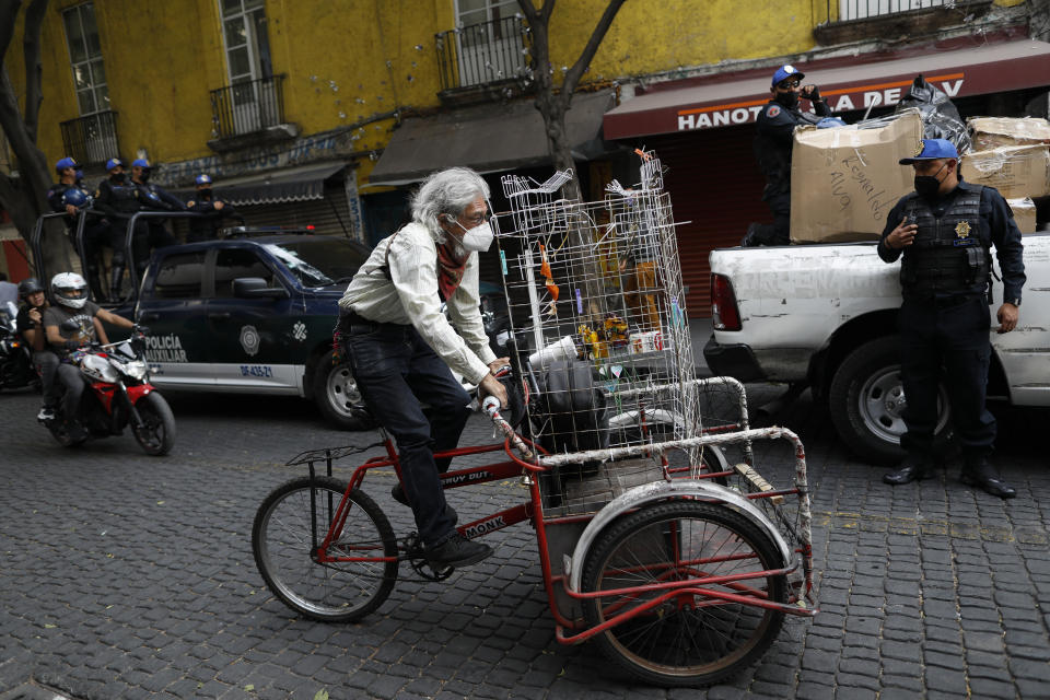 A man pedals away as police conduct operations to sanction street vendors and non-essential businesses operating in defiance of the city's "red alert" coronavirus regulations, in central Mexico City, Wednesday, Jan. 27, 2021. (AP Photo/Rebecca Blackwell)