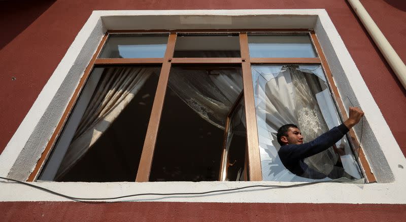 A man removes glass from a window that was allegedly damaged by recent shelling during the fighting over the breakaway region of Nagorno-Karabakh, in the city of Tartar