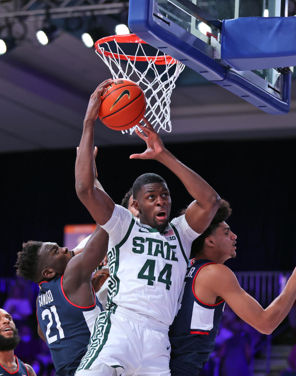 In this photo provided by Bahamas Visual Services, Michigan State forward Gabe Brown (44) grabs a rebound over Connecticut forward Adama Sanogo (21) and guard Andre Jackson (44) during an NCAA college basketball game at Paradise Island, Bahamas, Thursday, Nov. 25, 2021. (Tim Aylen/Bahamas Visual Services via AP)