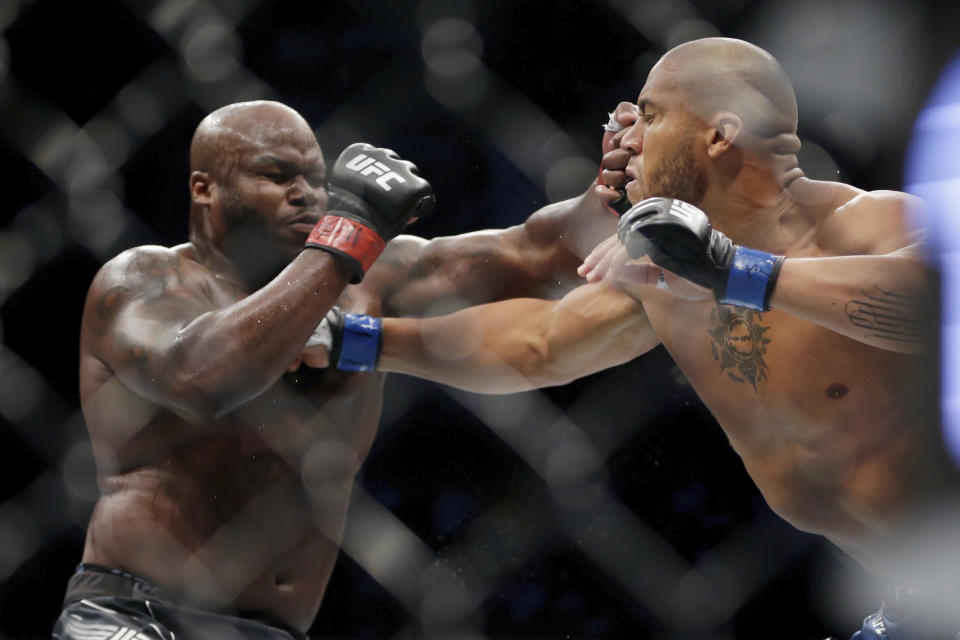 Derrick Lewis, left, takes a punch from Ciryl Gane during their interim heavyweight mixed martial arts title bout at UFC 265 on Saturday, Aug. 7, 2021, in Houston. (AP Photo/Michael Wyke)