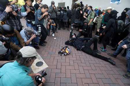 Protesters pose with a burning flag during the Patriots Day Free Speech Rally in Berkeley, California, U.S. April 15, 2017. REUTERS/Jim Urquhart