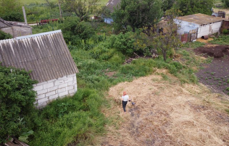 Local resident Hanna Plishchynska uses metal detector to find mines at a field near her house in the village of Stepova Dolyna