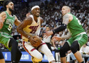 Miami Heat forward Jimmy Butler (22) drives to the basket between Boston Celtics guard Derrick White (9) and center Daniel Theis (27) during the second half of Game 1 of an NBA basketball Eastern Conference finals playoff series, Tuesday, May 17, 2022, in Miami. (AP Photo/Lynne Sladky)