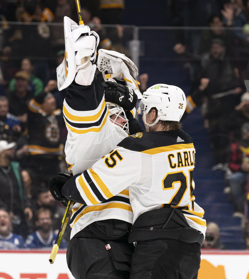 Boston Bruins goalie Linus Ullmark, left, celebrates his empty-net goal against the Vancouver Canucks with Brandon Carlo during the third period of an NHL hockey game in Vancouver, British Columbia, Saturday, Feb. 25, 2023. (Rich Lam/The Canadian Press via AP)