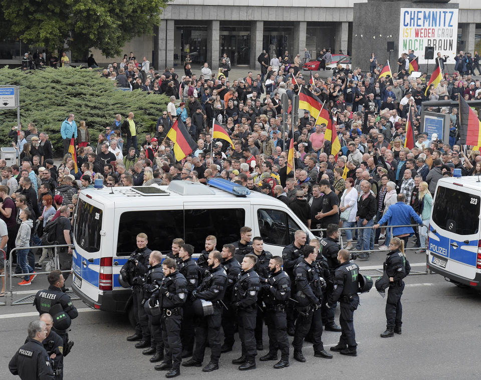 People are watched by police as they attend a demonstration in Chemnitz, eastern Germany, Friday, Sept.7, 2018, after several nationalist groups called for marches protesting the killing of a German man two weeks ago, allegedly by migrants from Syria and Iraq. (AP Photo/Jens Meyer)