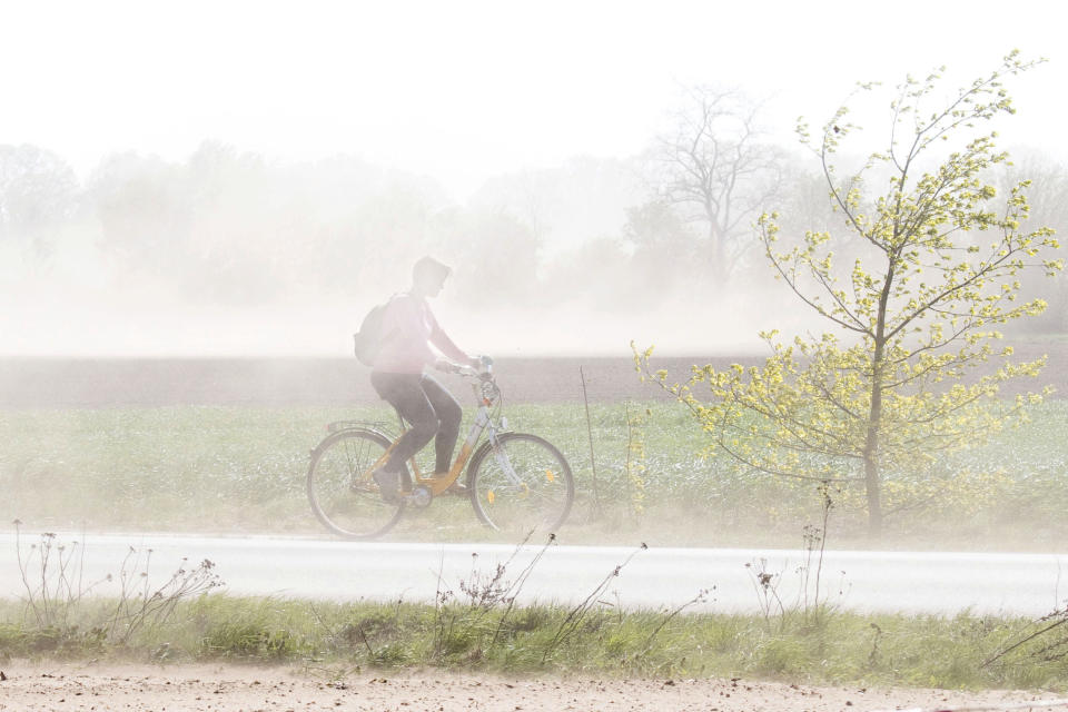 A cyclist makes his way through a heavy storm in Burgdorf, Germany, Tuesday, April 23, 2019. (Julian Stratenschulte/dpa via AP)