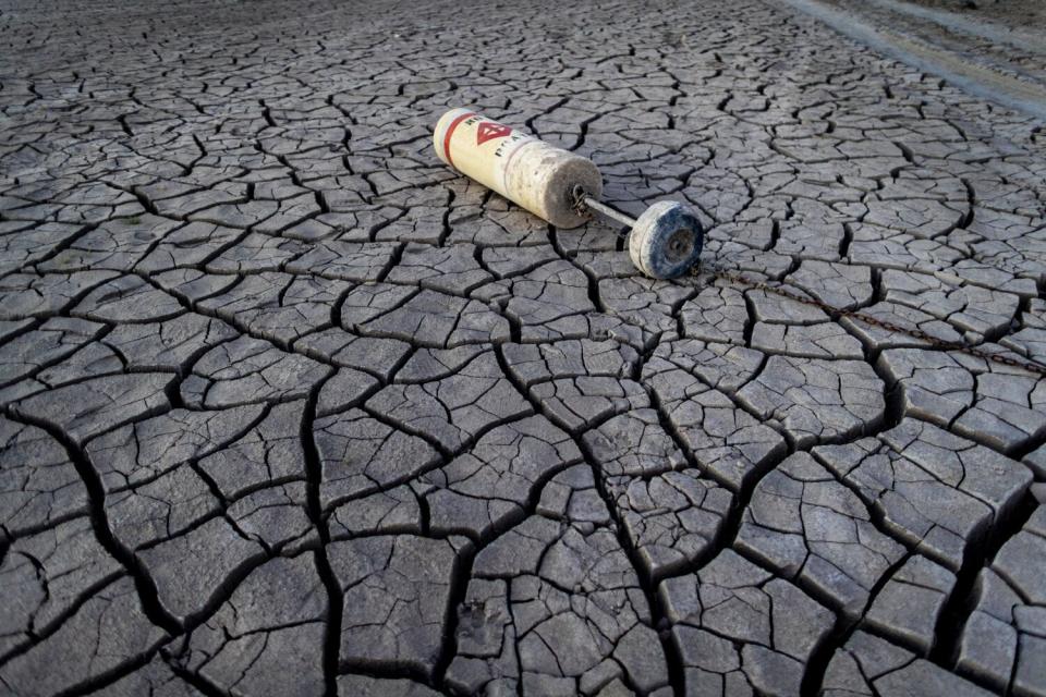 A buoy lies on a dried mud flat