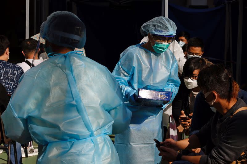 Medical workers in protective suits attend to people at a makeshift community testing centre for the coronavirus disease (COVID-19), in Hong Kong