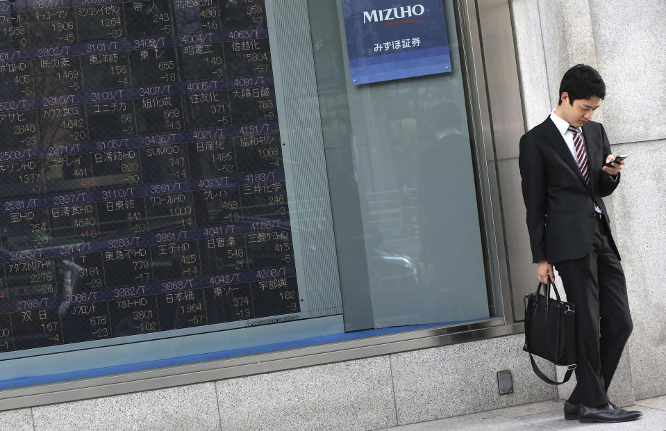 A man checks his mobile phone near an electronic stock board of a securities firm in Tokyo, Wednesday, April 9, 2014. Asian stocks were mostly higher Wednesday, except for Japan where the main index tumbled on a rise in the yen. (AP Photo/Eugene Hoshiko)