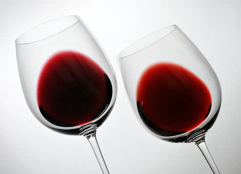 Two glasses of red wine are tilted.