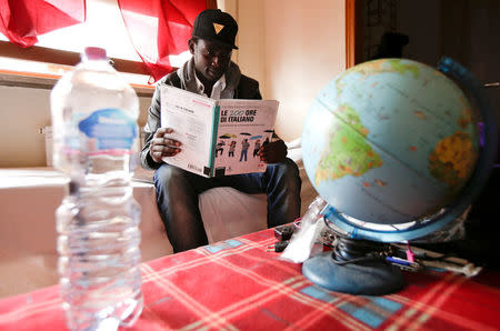 Yankouba Gassama, 21, from Gambia, poses holding a book of Italian grammar inside his room in a shelter in Rome, Italy, November 23, 2016. Picture taken November 23, 2016. REUTERS/Max Rossi