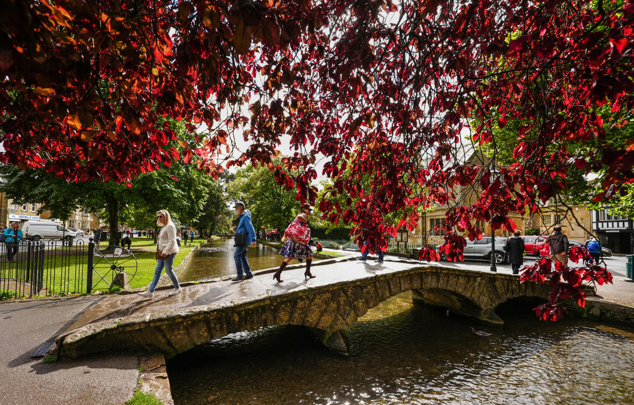 People cross a bridge over the River Windrush in Bourton on the Water, in the Cotswolds, on Thursday. (PA)