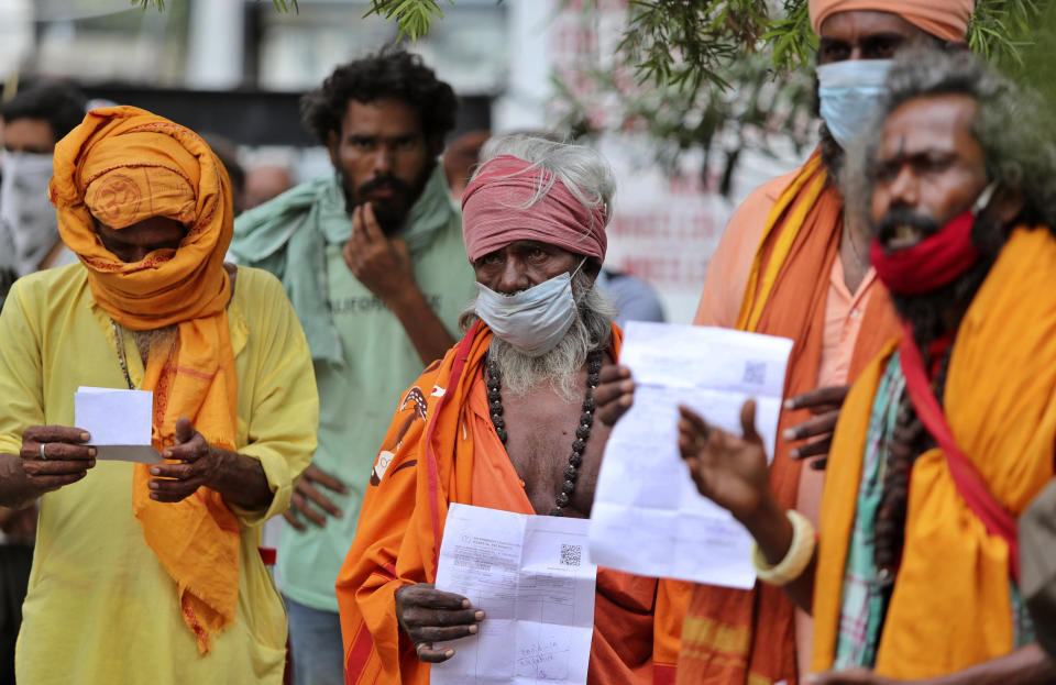 Hindu holy men wearing face masks wait to consult doctors at a COVID-19 screening facility inside a government hospital in Jammu, India, Tuesday, July 21, 2020. With a surge in coronavirus cases in the past few weeks, state governments in India have been ordering focused lockdowns in high-risk areas to slow down the spread of infections.(AP Photo/Channi Anand)